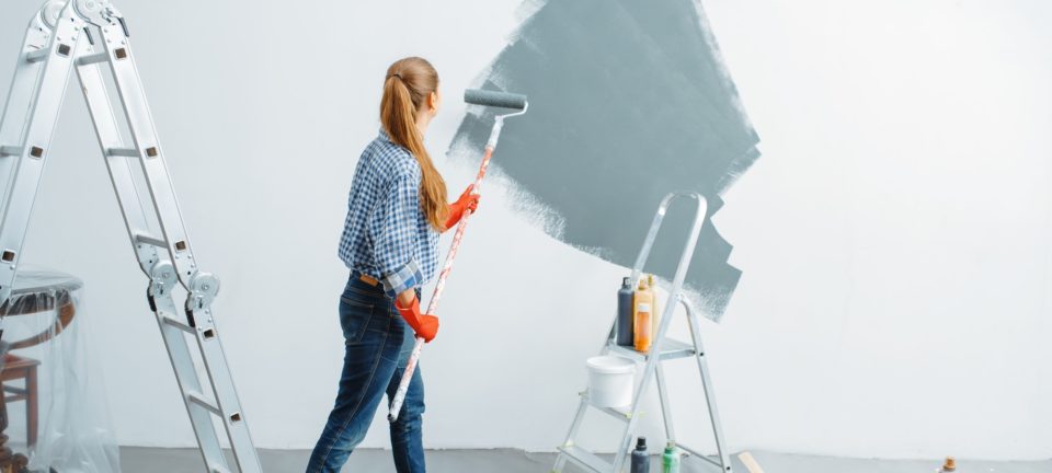 Female house painter paints wall