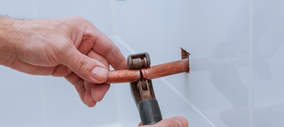 hand of working cutting copper pipe plumbing